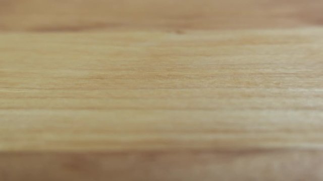 Slow forward movement across natural wood surface parallel to grain. Close up with shallow depth of field.