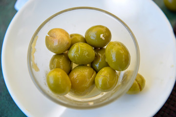 Homemade green olives on a white plate.