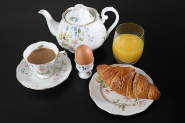 Continental breakfast with a teapot on a black table