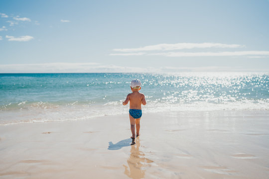 boy walking into the water at the beach on a sunny day on vacation