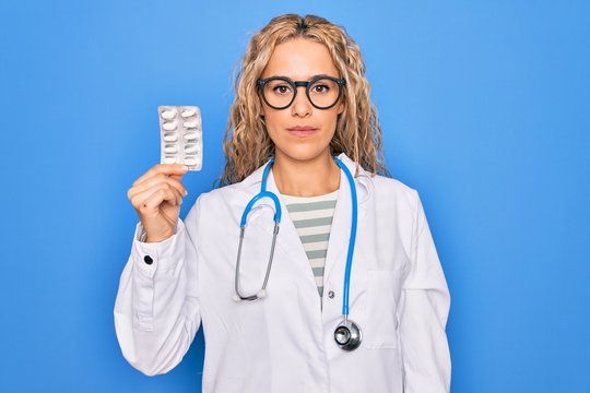 Young beautiful blonde cardiologist woman wearing stethoscope holding plastic heart thinking attitude and sober expression looking self confident