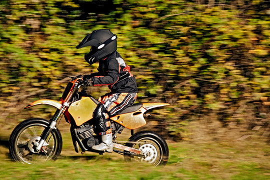 12 year old boy riding his motocross motorcycle through field