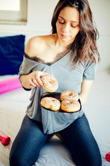 Pretty woman holding chocolate donuts and dumbbell. Food concept.