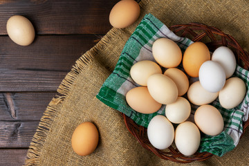 Top view of an eggs in a basket with a napkin on a wooden background.