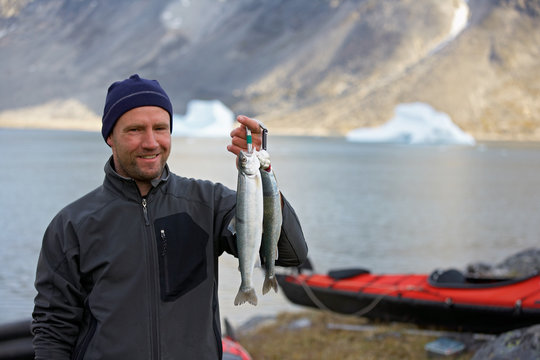 man holding up fresh Arctic Char in Greenland