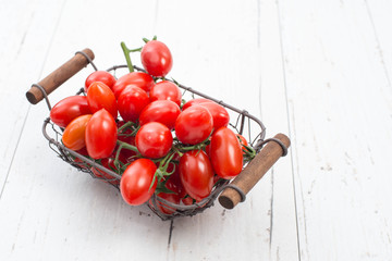 Red cherry tomatoes on a white textured background, empty copy space for text