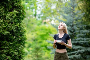 Blonde woman with cup of coffee in a park