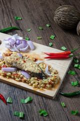 Steam salted King mackerel fish with minced garlic and chili salad on wooden background. ( Spicy Thai Food call Yum Pla Kem )