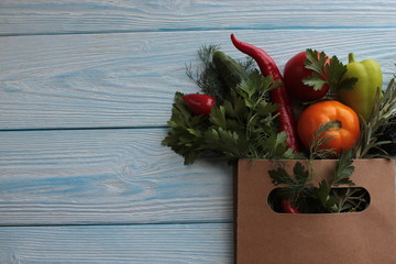Paper bag with vegetables and herbs on the table.
