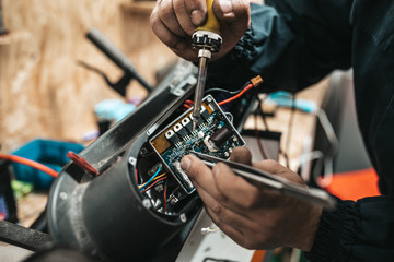 Man repairing electrical scooter in special workshop.