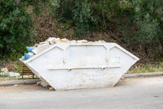 Loaded skip bin with waste on a road.