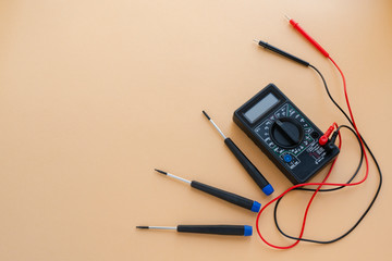 multimeter and screwdriver on a yellow background. Flatlay, copy space