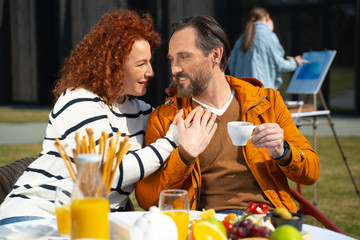 Happy married couple sharing tender moment during breakfast outdoors