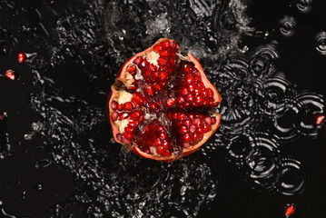 Pomegranate on the black background in the water.