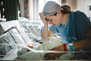Sad and depress Mother with her newborn baby at the hospital a day after a natural birth labor
