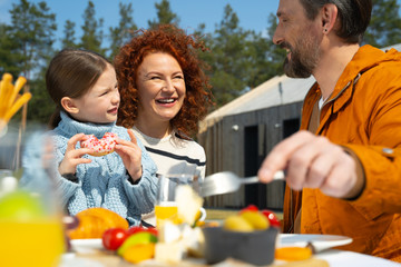 Cheerful woman having breakfast with husband and daughter