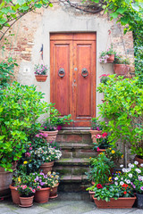 Flowers and greenery contribute to Old World romance and elegance when surrounding a door in a Tuscan alley in Pienza, Italy