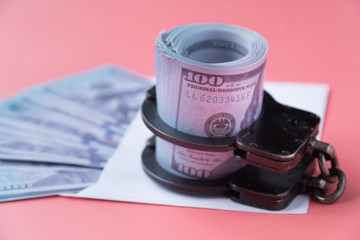 handcuffs on an envelope with money, pink background