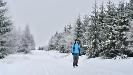 A young woman walks on the snow along a tourist trail.