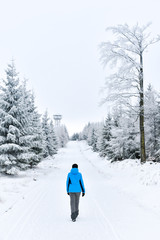 A young woman walks on the snow along a tourist trail.