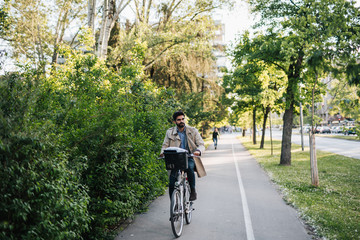 Positive young man riding a bicycle to work.