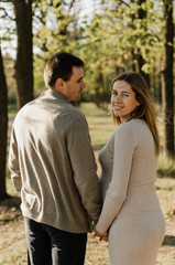 Fototapeta premium happy young pregnant couple walks in the park,husband holds the hand of his pregnant wife,future dad and mom,walks in the park after quarantine