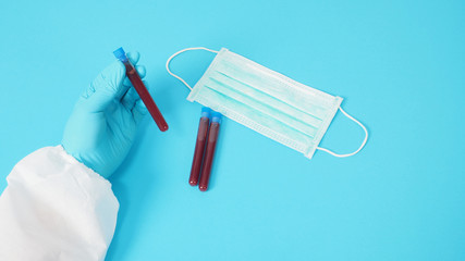 Male model with PPE suite and Hand wearing glove is holding face mask. Blood collection tubes on...