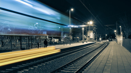 The train passed a railway station, people are waiting on the platform for the next train.