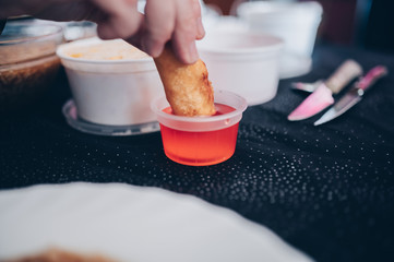 Smearing spring roll in sweet and sour sauce.Eating chinese food at home.Focus selective.