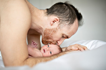 Fototapeta na wymiar A father with a newborn baby in bed