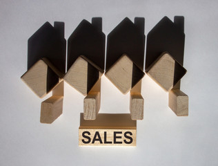 Houses created by shadows from wooden cubes. The word 'sales' on a wooden block.