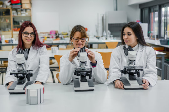 Female scientists using microscopes in lab