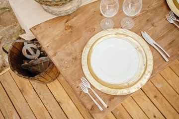 From above top view wooden table decorated with white and golden plates with wooden floor on in background