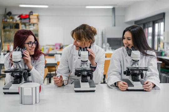 Female scientists using microscopes in lab