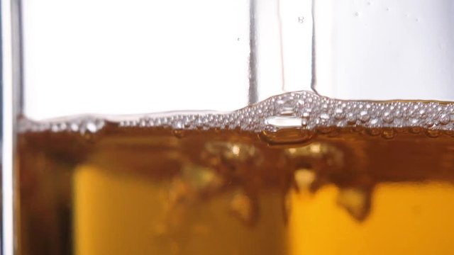 Apple juice pours into a glass, macro shooting slow motion