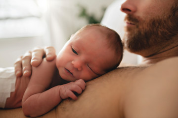 A father with a newborn baby in bed