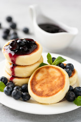 Cheese fritters Syrniki with blueberry jam on white plate. Russian Ukrainian cuisine healthy breakfast food