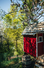 red wooden playing hut for children with blooming apple trees in the garden in spring