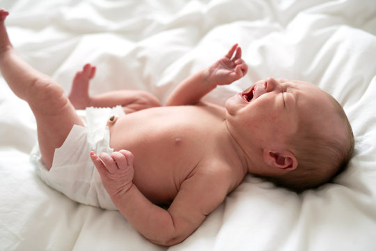A cute Newborn baby crying in bed