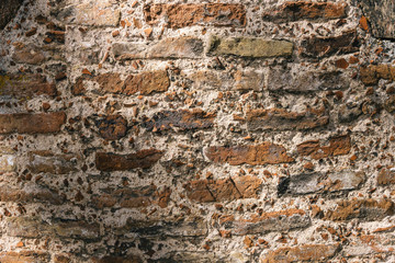 Old brick wall texture. Weathered wall surface. Grungy orange brickwall. Red stonewall background. Shabby building facade on sunny day. Old brown stone wall in city. Vintage backdrop with row brick.