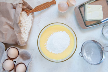 Ingredients for making dough for homemade pancakes for breakfast. On the table are wheat flour, eggs, butter, sugar, salt, milk. Selective focus. Sequencing