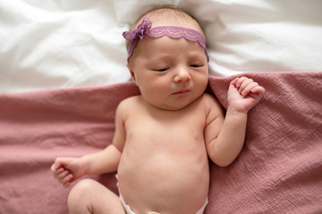 Cute newborn baby girl on the white bed