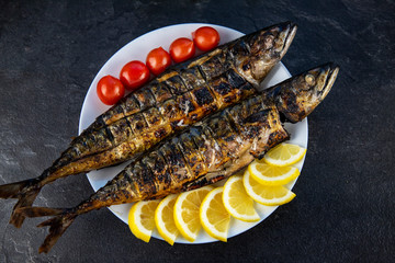 Grilled mackerel fish in a pan with vegetables. horizontal view from above