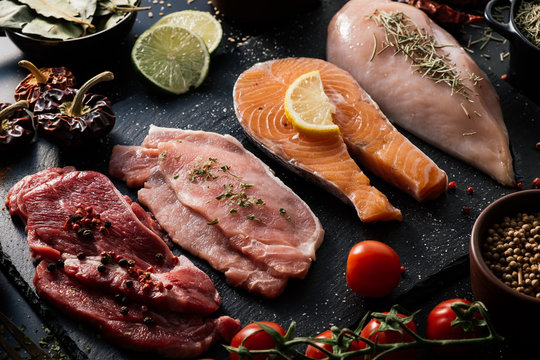 Flat lay of proteins surrounded by spices and seasonings on table