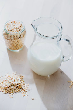 Jar of milk and oatmeal flakes on table