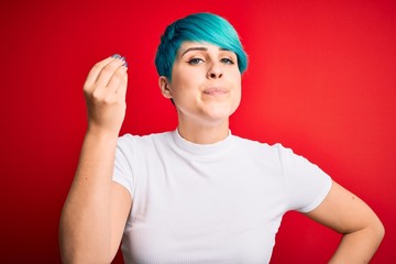 Fototapeta na wymiar Young beautiful woman with blue fashion hair wearing casual t-shirt over red background Doing Italian gesture with hand and fingers confident expression