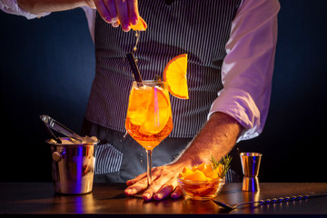 Bartender sprinkling Aperol spritz cocktail glass with orange juice