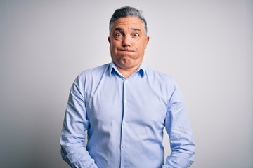 Middle age handsome grey-haired business man wearing elegant shirt over white background puffing cheeks with funny face. Mouth inflated with air, crazy expression.