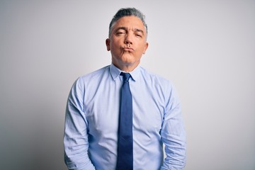 Middle age handsome grey-haired business man wearing elegant shirt and tie looking at the camera blowing a kiss on air being lovely and sexy. Love expression.