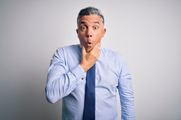 Middle age handsome grey-haired business man wearing elegant shirt and tie Looking fascinated with disbelief, surprise and amazed expression with hands on chin